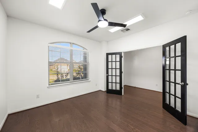 a view of an empty room with a window and wooden floor