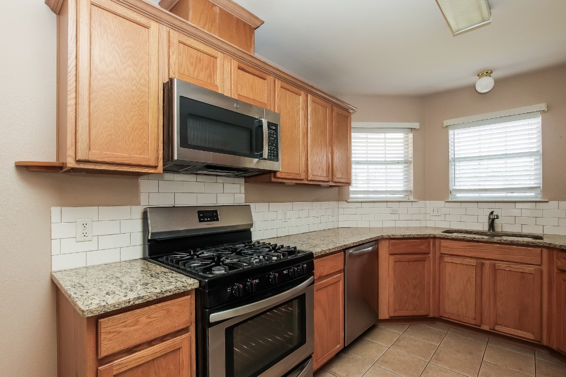 21304 Secretariat Ridge Lane Pflugerville, TX 78660 - Photo 11 of 29 a kitchen with granite countertop a sink stove and microwave