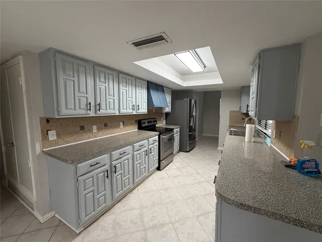 a kitchen with kitchen island granite countertop a sink counter top space and stainless steel appliances