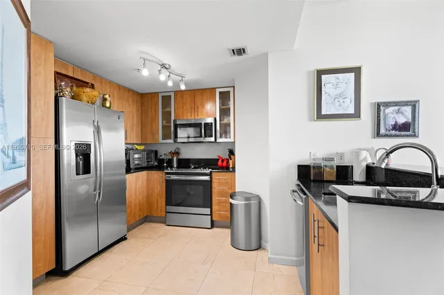 a kitchen with stainless steel appliances granite countertop a refrigerator a stove top oven and sink