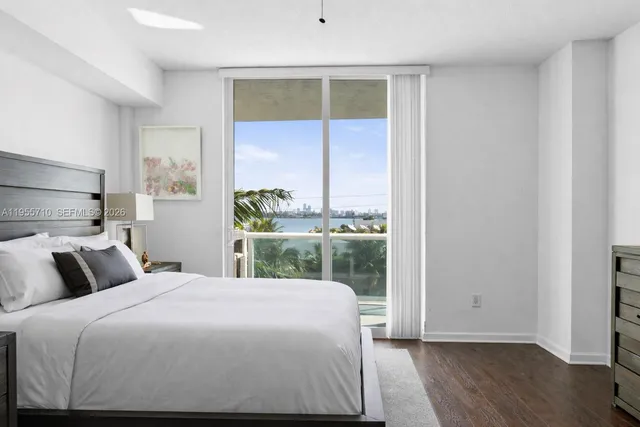 a bedroom with a large window and a wooden floor