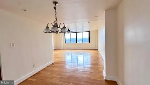 a view of a hallway with wooden floor and a chandelier