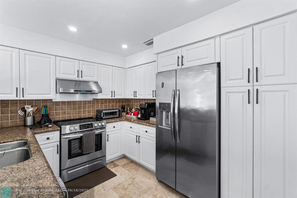 2058 Northwest 52nd Street Boca Raton, FL 33496 - Photo 8 of 35 a kitchen with a refrigerator sink and cabinets