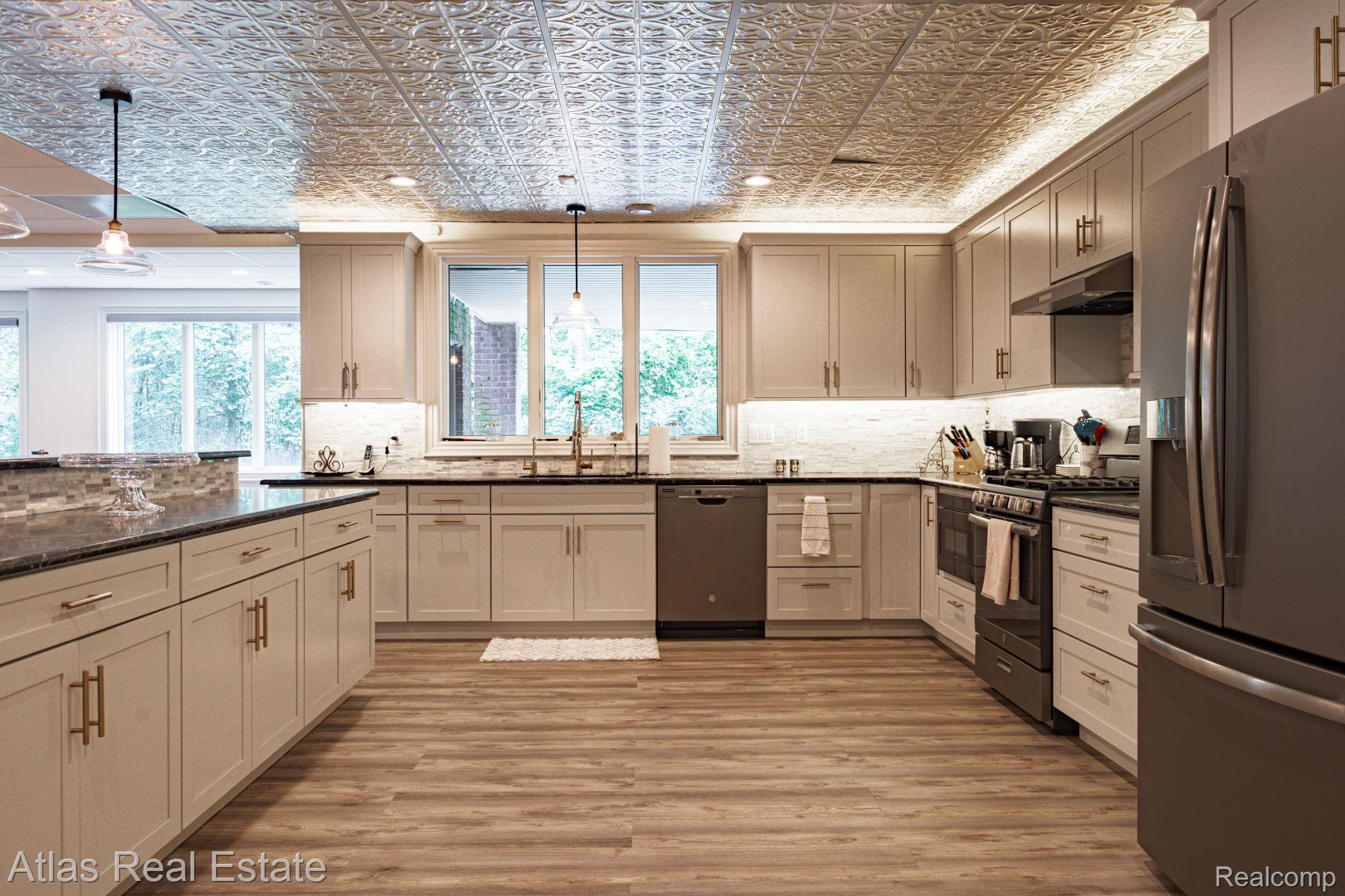 10380 South State Road Goodrich, MI 48438 - Photo 80 of 87 Kitchen featuring a pressed tin ceiling, wood-finish flooring, light cabinetry with gold-tone hardware, dark countertops, and stainless steel appliances
