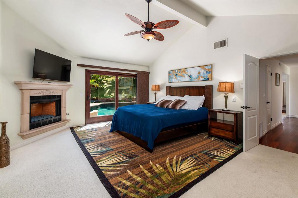 6541 Vispera Place Carlsbad, CA 92009 - Photo 23 of 54 a bedroom with a large bed a flat tv screen and a fireplace