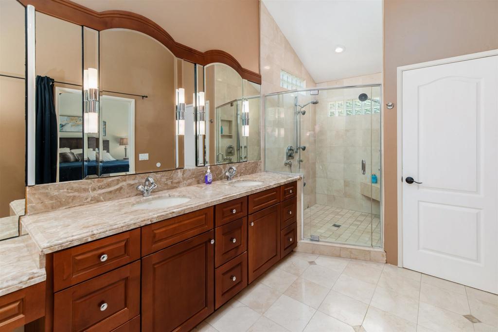 6541 Vispera Place Carlsbad, CA 92009 - Photo 24 of 54 a bathroom with a granite countertop sink mirror and shower