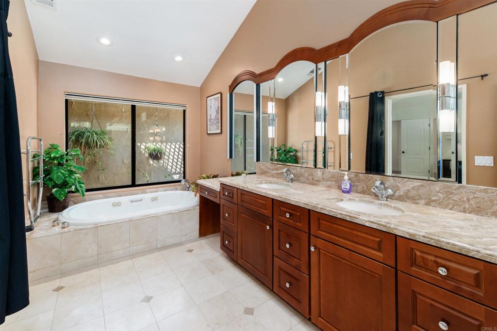 6541 Vispera Place Carlsbad, CA 92009 - Photo 25 of 54 a spacious bathroom with a granite countertop tub mirror and a sink