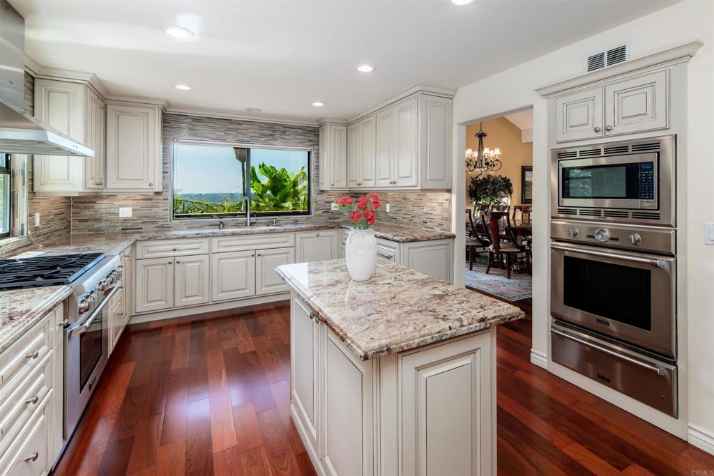 6541 Vispera Place Carlsbad, CA 92009 - Photo 6 of 54 a kitchen with stainless steel appliances kitchen island granite countertop a stove refrigerator and microwave