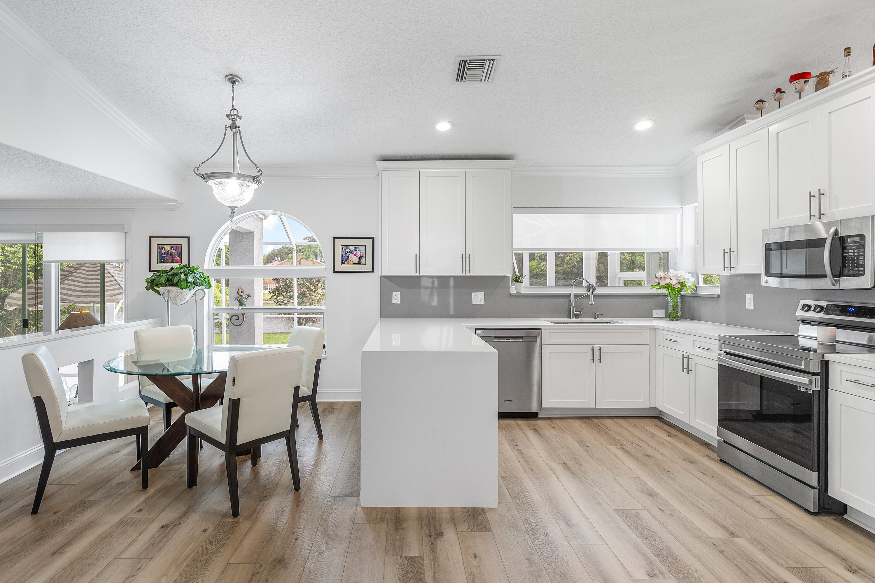 10824 Tea Olive Lane Boca Raton, FL 33498 - Photo 13 of 76 a kitchen with a table chairs microwave and cabinets