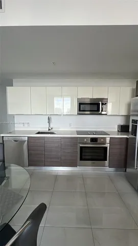 a kitchen with stainless steel appliances kitchen island a table chair in it and white cabinets