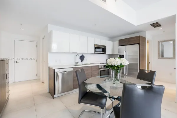 a kitchen with stainless steel appliances a dining table chairs and refrigerator