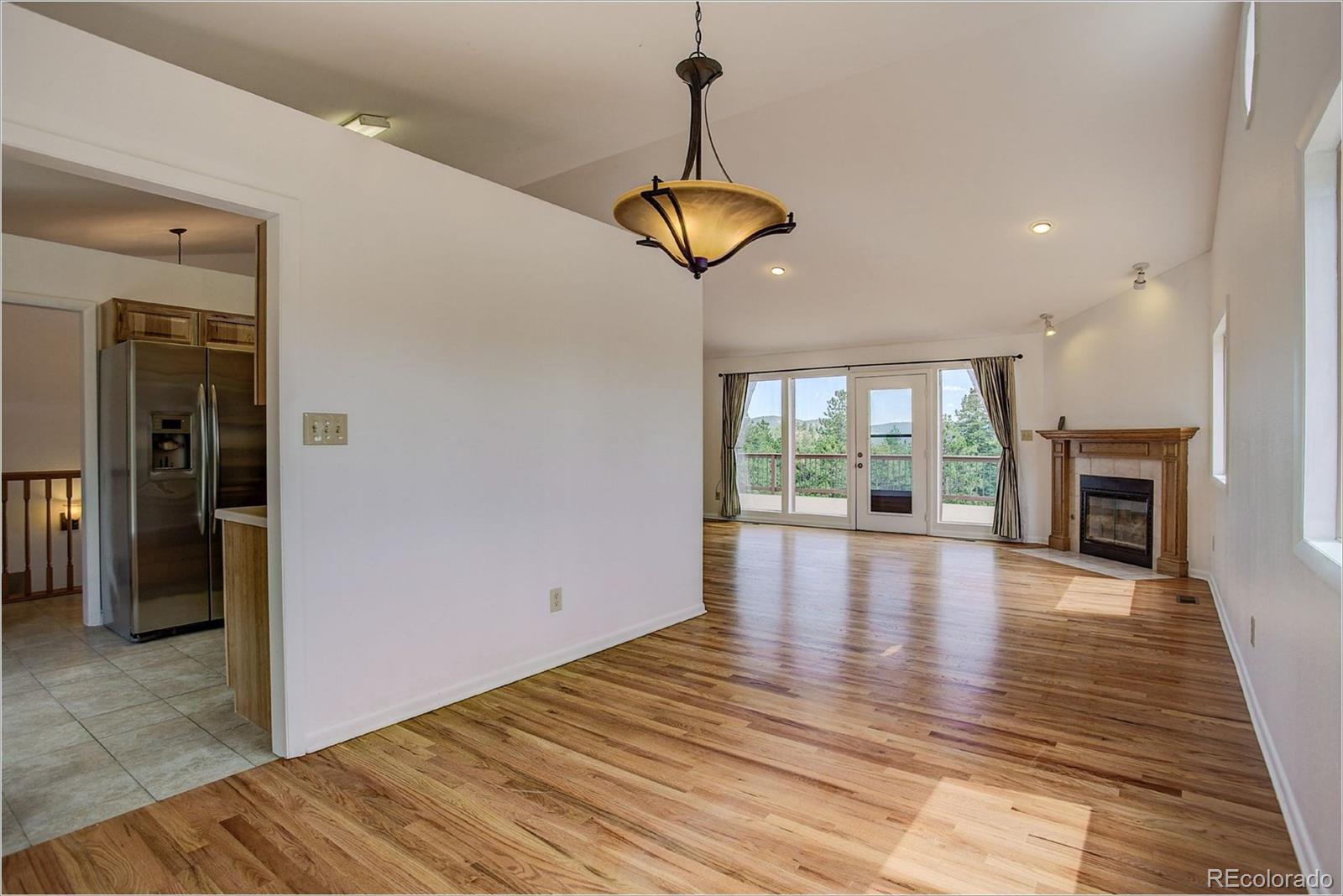 763 Desperado Road Bailey, CO 80421 - Photo 8 of 32 a view of an empty room with wooden floor fireplace and a window