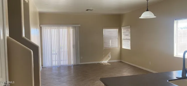 an empty room with windows and a chandelier fan