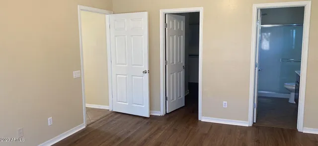 an empty room with wooden floor & bathroom view