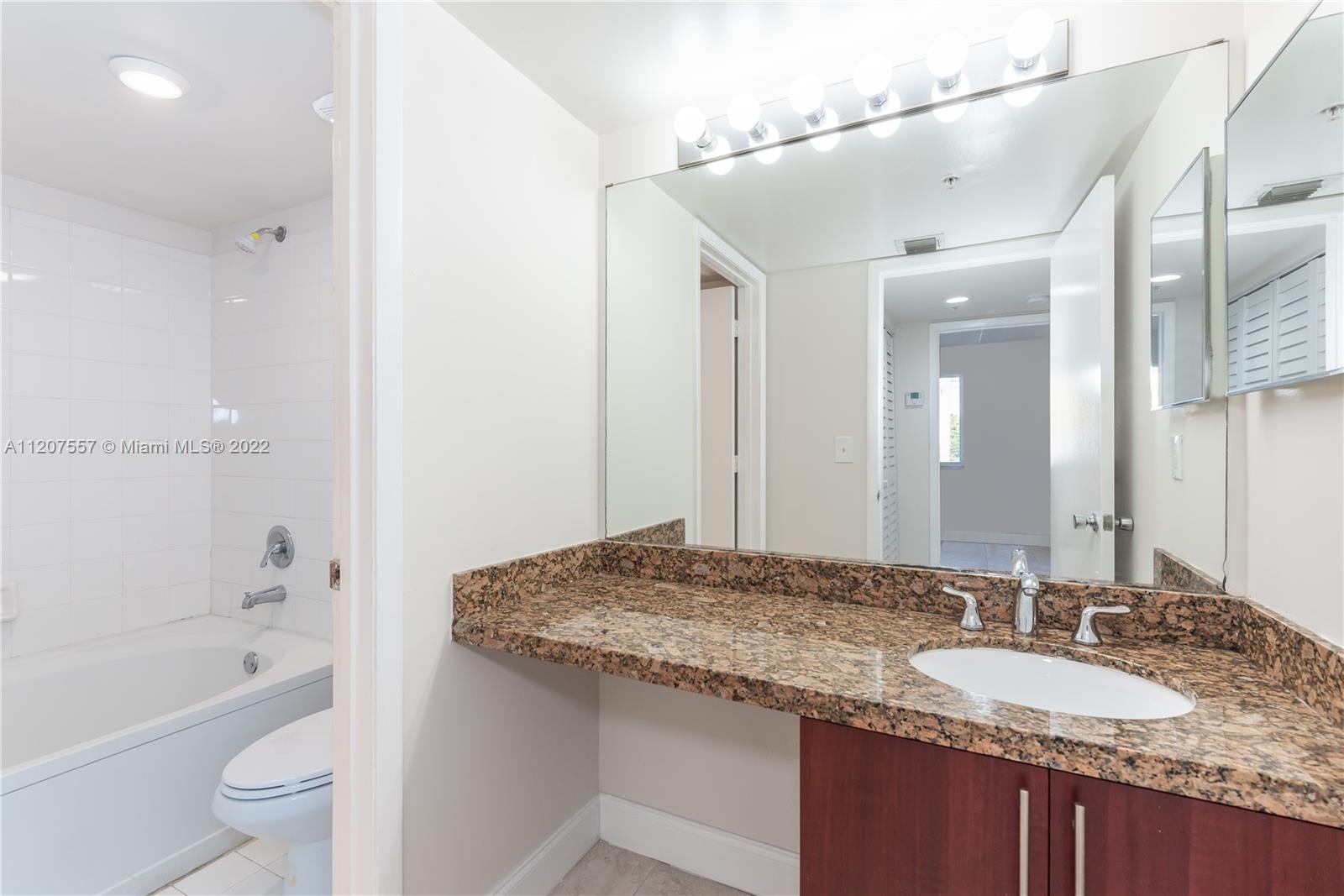 771 North Pine Island Road, Unit 203 Plantation, FL 33324 - Photo 12 of 20 a bathroom with a granite countertop sink a toilet a mirror a bathtub and shower