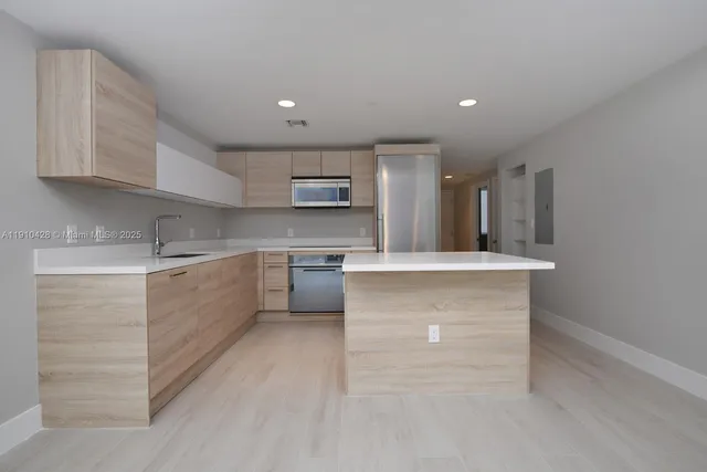 a large kitchen with kitchen island a sink stainless steel appliances and cabinets