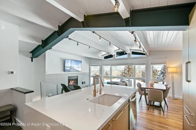 a kitchen with a table chairs refrigerator and wooden floor