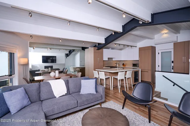 a living room with furniture a chandelier and kitchen view