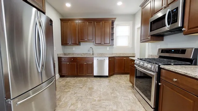 a kitchen with stainless steel appliances granite countertop a refrigerator stove and sink