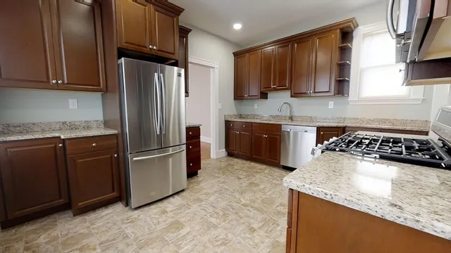 a kitchen with stainless steel appliances granite countertop a stove a refrigerator and a sink