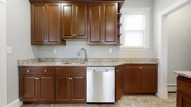 a kitchen with granite countertop wooden cabinets a sink and dishwasher