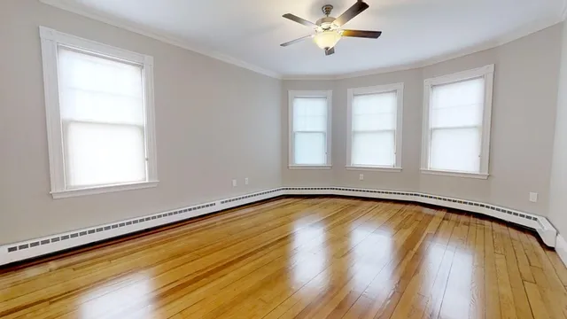a view of an empty room with a window and wooden floor