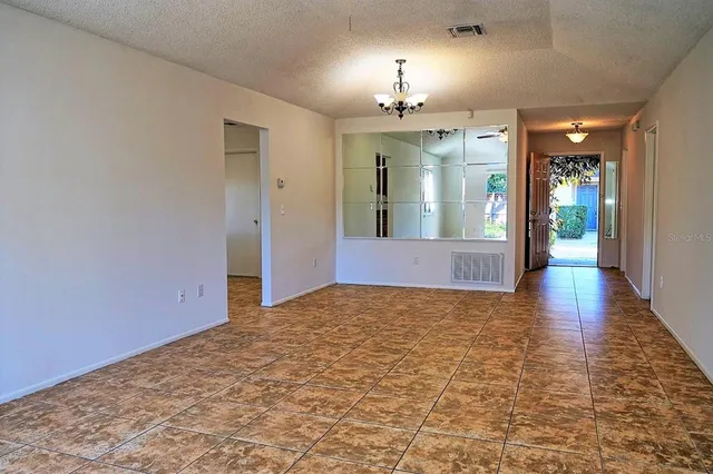 a view of an empty room and kitchen with a chandelier