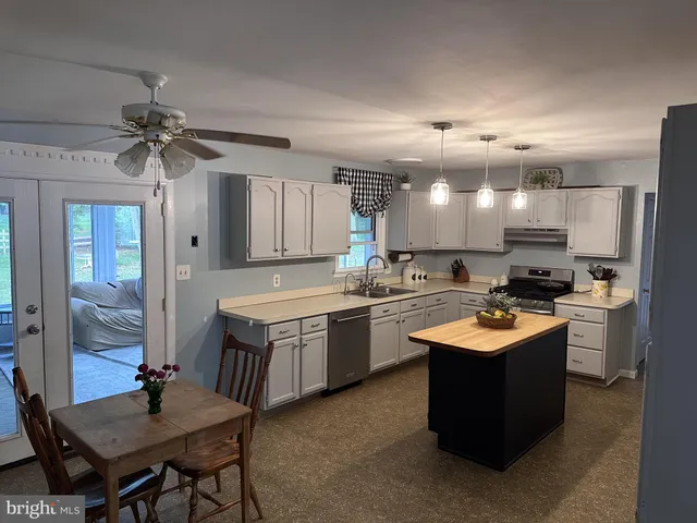 a large kitchen with kitchen island a sink a stove a refrigerator and a dining table with wooden floor