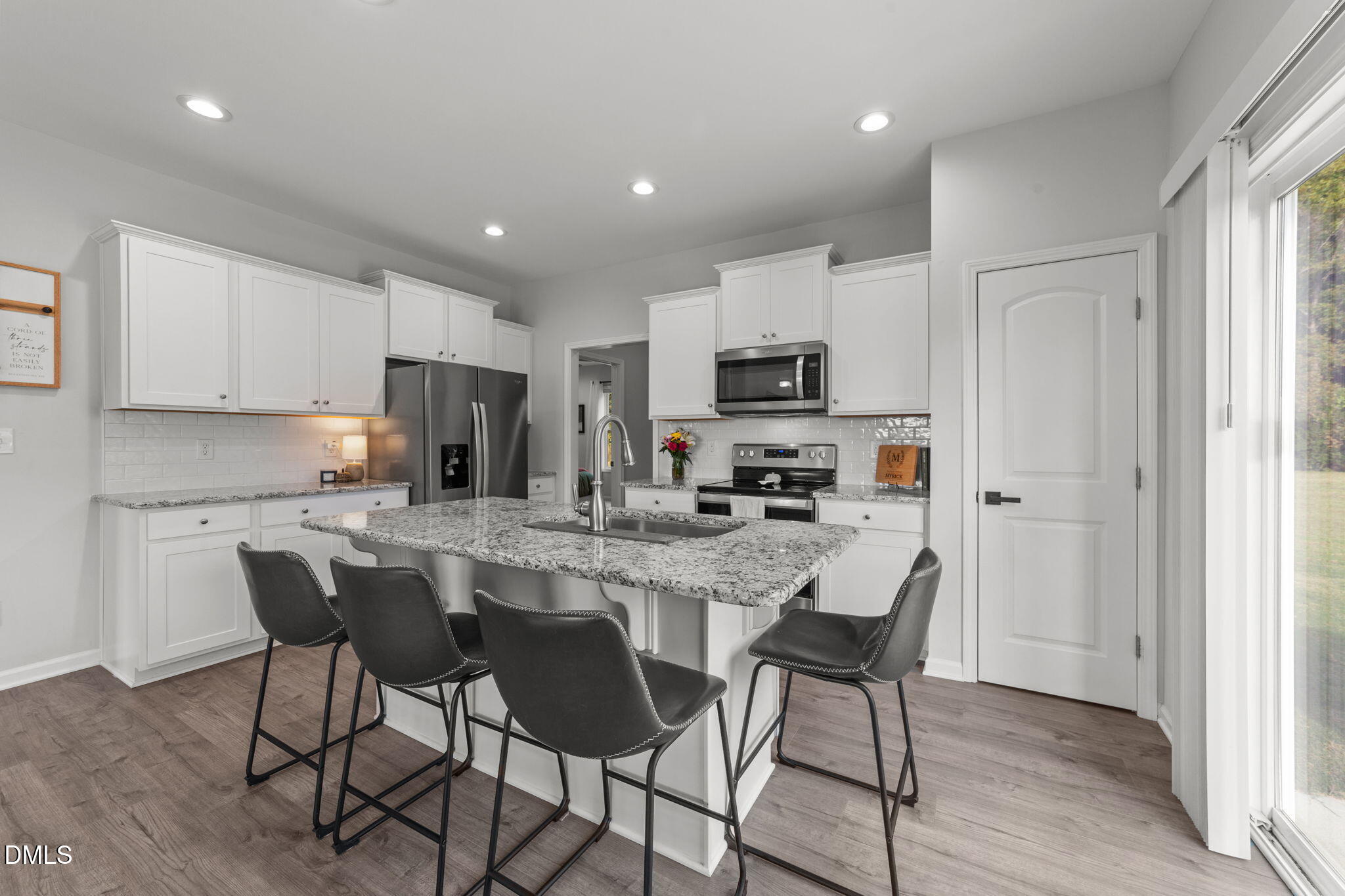 67 Overdrift Court Selma, NC 27576 - Photo 12 of 36 a kitchen with stainless steel appliances granite countertop a stove a sink a microwave a refrigerator and white cabinets with wooden floor