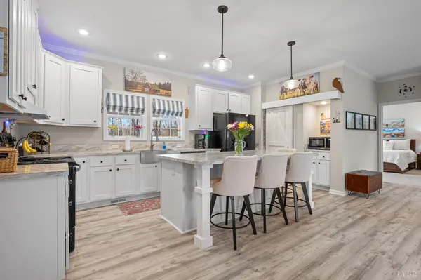 a kitchen with stainless steel appliances kitchen island granite countertop a refrigerator a stove a microwave oven a dining table and chairs with wooden floor
