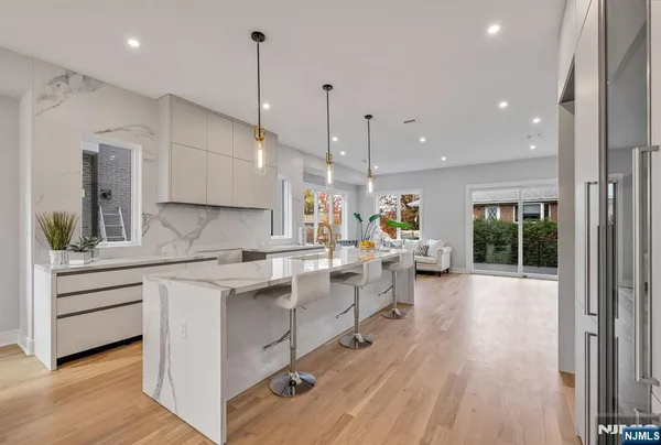 a kitchen with sink stove and white cabinets with wooden floor