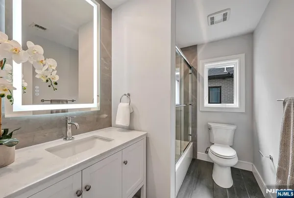 a bathroom with a toilet sink a mirror and vanity