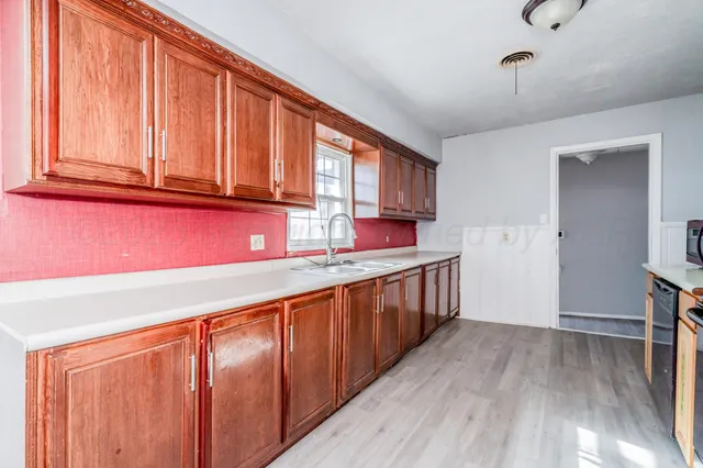 a kitchen with stainless steel appliances granite countertop wooden cabinets a sink and dishwasher with wooden floor