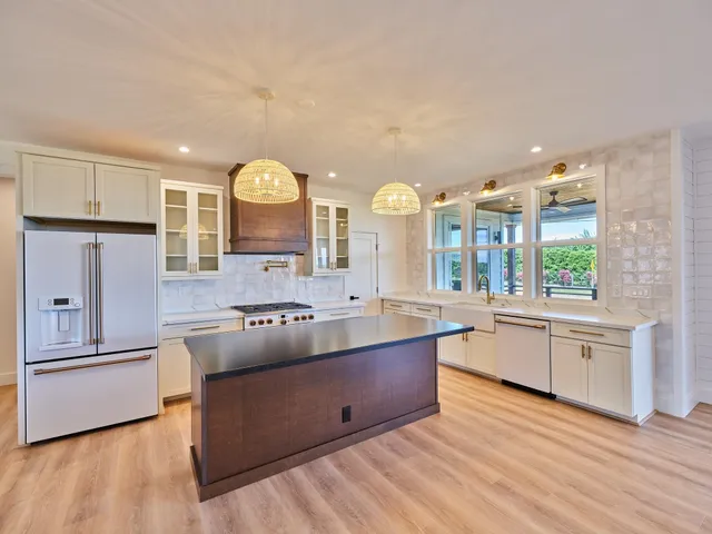 a kitchen with stainless steel appliances granite countertop a sink a stove and wooden floors