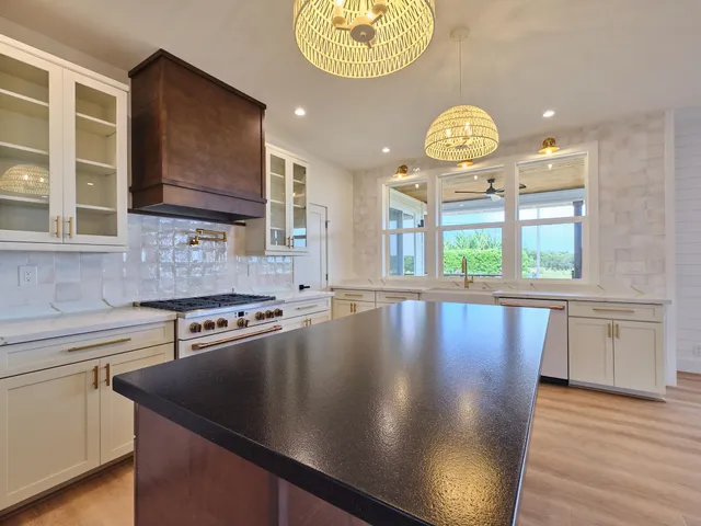 a view of a kitchen with stainless steel appliances granite countertop a stove top oven a sink and dishwasher with wooden floor