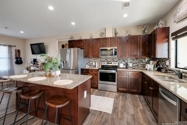 a kitchen with stainless steel appliances kitchen island granite countertop a sink stove and refrigerator