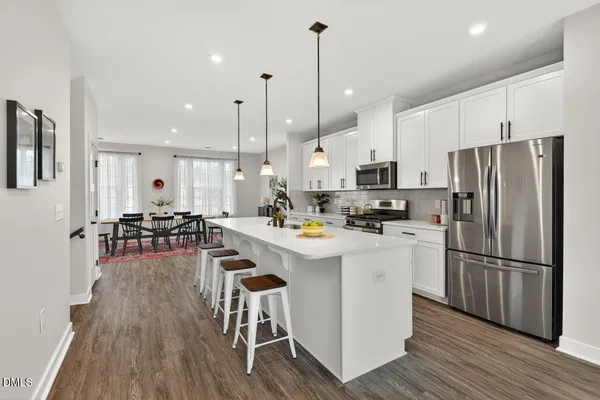 a kitchen with stainless steel appliances a stove a sink a microwave a refrigerator a center island and chairs