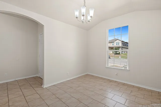 an empty room with chandelier fan and windows