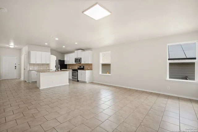 a view of kitchen with kitchen island granite countertop white cabinets and refrigerator