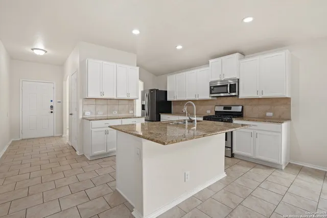 a kitchen with kitchen island granite countertop stainless steel appliances cabinets a sink and a counter top space
