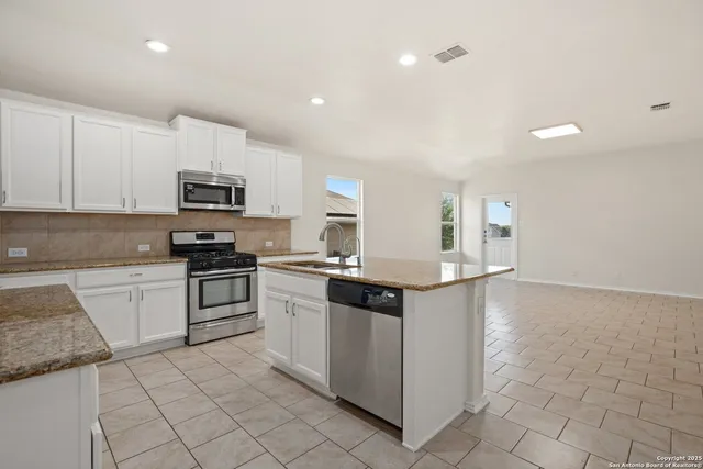 a kitchen with stainless steel appliances granite countertop a stove top oven a sink a microwave and a refrigerator