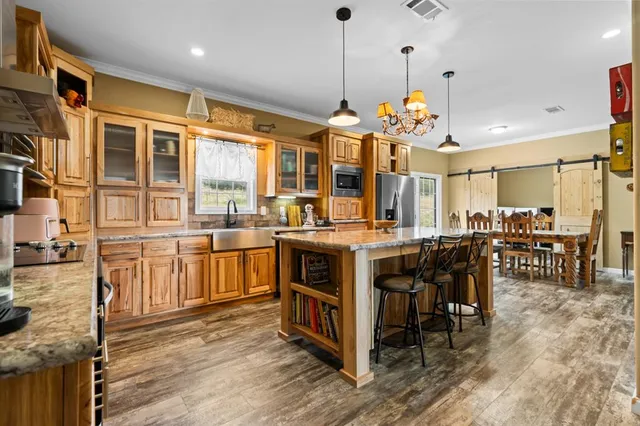 a view of a kitchen with stainless steel appliances granite countertop a stove oven a dining table and chairs with wooden floor