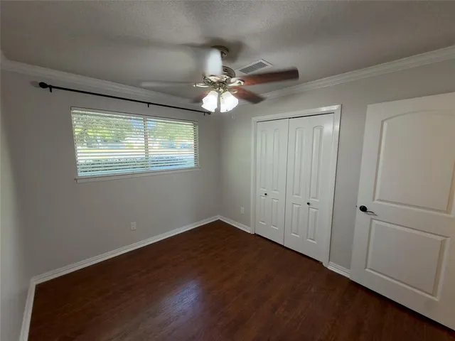 a view of an empty room with window and chandelier fan