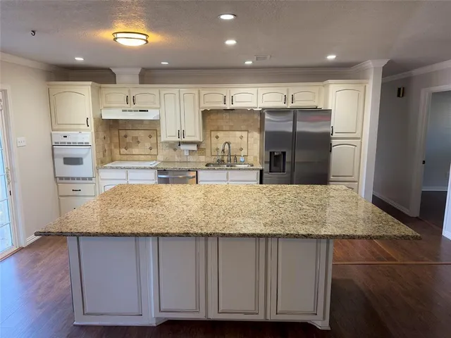 a kitchen with kitchen island granite countertop a sink refrigerator and cabinets