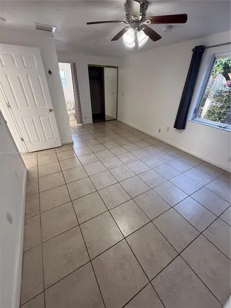 an empty room with windows and fan