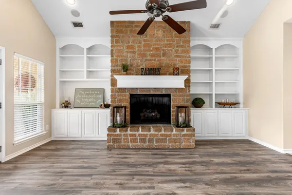 a view of a livingroom with a fireplace a ceiling fan and window