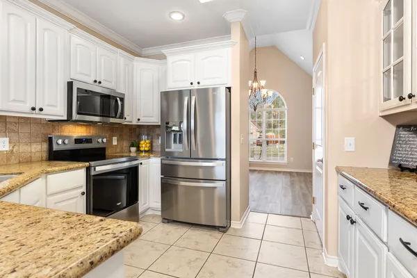 a kitchen with granite countertop a refrigerator and a stove top oven