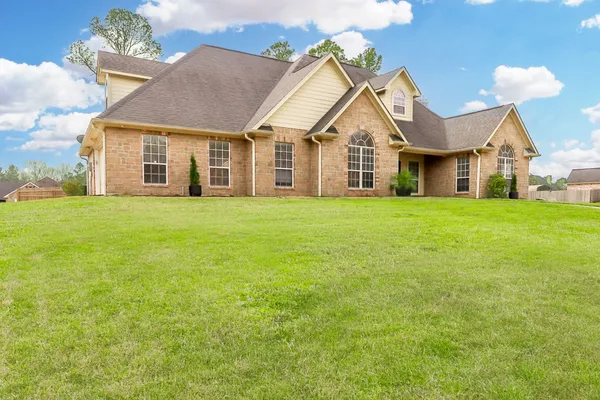 a view of a big house with a big yard and large trees
