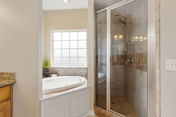 a bathroom with a tub shower sink and mirror
