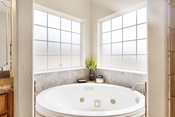 a white bath tub sitting in a bathroom next to a window